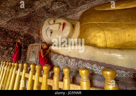 Buddista monaco novizio / little monk / giovane monaco culto bella grande Buddha reclinato statua nella grotta Phowintaung Monywa Myanmar Foto Stock