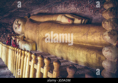 Buddista monaco novizio / little monk / giovane monaco culto bella grande Buddha reclinato statua nella grotta Phowintaung Monywa Myanmar Foto Stock