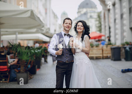 Sposa e lo sposo a piedi lungo una città solare e mangiare il gelato Foto Stock