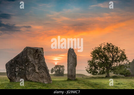 Le nuvole parte come Aurora rompe su antiche pietre Sarsen ad Avebury nel Wiltshire il giorno prima del solstizio d'estate. Foto Stock