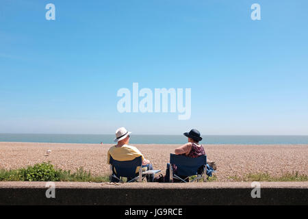 Aldeburgh Suffolk REGNO UNITO Giugno 2017 - coppia seduta indossando cappello da sole con cielo azzurro sul lungomare Foto Stock