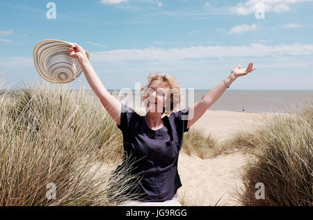 Southwold Suffolk REGNO UNITO Giugno 2017 - donna di mezza età con cappello per il sole su Southwold Beach e le dune di sabbia Foto Stock