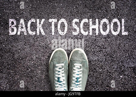 Parole torna a scuola scritto su strada asfaltata con scarpe da ginnastica, high school e college di concetto Foto Stock