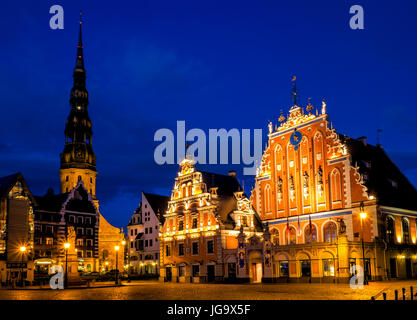 RIGA, Lettonia - CIRCA NEL MAGGIO 2014: vista notturna della piazza della città di Hall con "La Casa delle Teste Nere' e la chiesa di San Pietro nella città vecchia di Riga di notte. Foto Stock