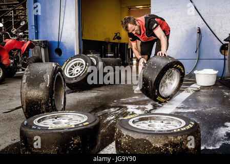 Lavoro meccanico nel circuito pit la pulizia ed il lavaggio di racing serie di pneumatici Foto Stock