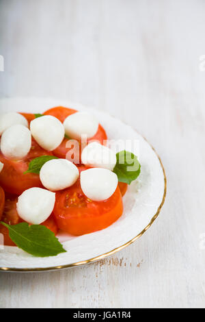 Insalata caprese su un tavolo di legno. deliziosa insalata con mozzarella, pomodoro e basilico. Foto Stock