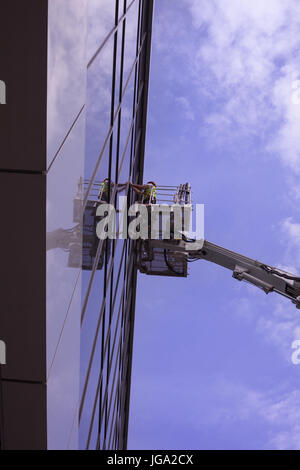 Uomo sulla piattaforma di lavoro > acrobatici, profesjonal opere - Pulizia finestrino Foto Stock