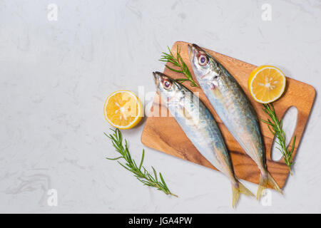 Piatto di pesce in cucina con vari ingredienti. Fresco pesce crudo decorate con le fette di limone e le erbe sul tavolo di legno. Foto Stock