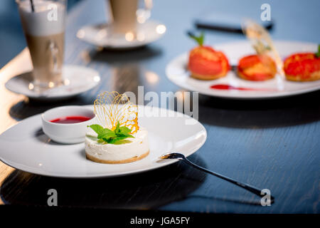 Vista ravvicinata di gustosi dessert con tazzine di caffè sul tavolo nel ristorante Foto Stock