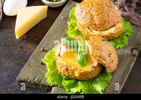 Deliziosi piatti cotti burger dal bacon, uova, formaggio servita con fresche foglie di lattuga. Ingredienti per la cottura di uova strapazzate. Foto Stock