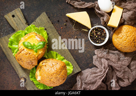 Deliziosi piatti cotti burger dal bacon, uova, formaggio servita con fresche foglie di lattuga. Ingredienti per la cottura di uova strapazzate. Vista dall'alto. Foto Stock