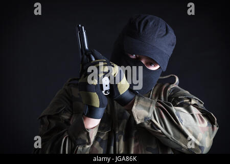 Anti terrorista in possesso di una pistola, guardando la fotocamera su sfondo nero Foto Stock
