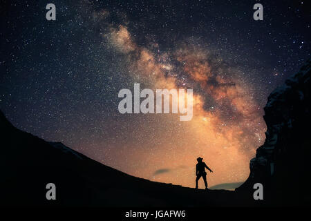 Un uomo è in piedi accanto alla via lattea. Foto Stock