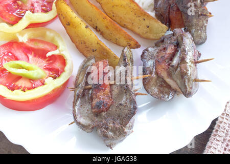 Pollo fritto il fegato e la pancetta da vicino nella piastra Foto Stock