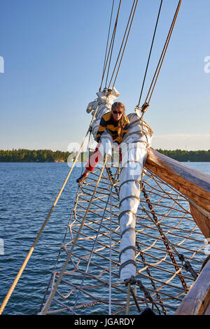 Astrid (Finlandia) TS 488 Gaff Ketch in legno barca a vela 1947 - membro di equipaggio avvolgifiocco e stivare le vele di prua Foto Stock