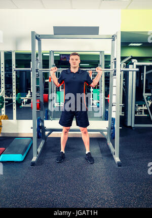 Uomo bello in sollevamento sportswear barbells cercando focalizzata, lavorando in una palestra Foto Stock