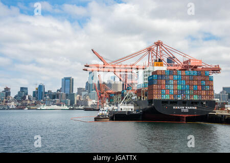 Ocean andando nave container di caricamento con gru a portale e di rifornimento nel porto di Seattle con Skyline in background Foto Stock