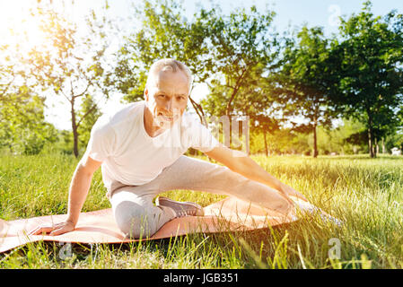 Lieto uomo più anziano facendo esercizi di stretching Foto Stock