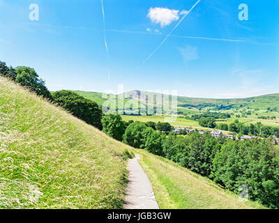 Da una ripida Derbyshire hillside su un luminoso giorno nebuloso, la città di Castleton è di gran lunga al di sotto e Mamtor direttamente davanti. Foto Stock