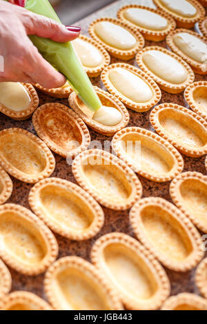 La preparazione di piccole tortine di pasta riempita con crema alla vaniglia Foto Stock