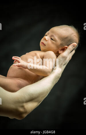 A 3 settimane di età baby figlio recante sulla sua mano del padre Foto Stock