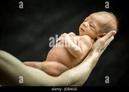 A 3 settimane di età baby figlio recante sulla sua mano del padre Foto Stock