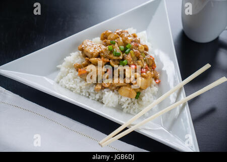 Lastra di Kung Pao pollo su piastra bianca con bacchette. Foto Stock