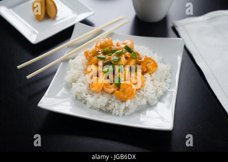 Il Szechuan gamberi e riso con le cipolle verdi sulla piastra bianca con bacchette. Foto Stock