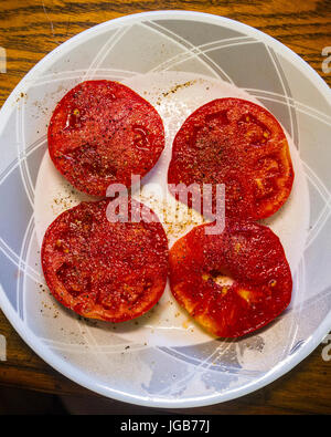 Una piastra di fettine di pomodori cresciuti in casa con sale e pepe Foto Stock