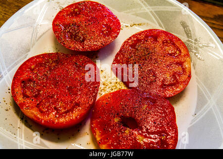 Una piastra di fettine di pomodori cresciuti in casa con sale e pepe Foto Stock