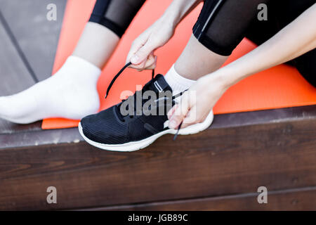 La donna si lega a sua lacci delle scarpe Foto Stock