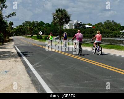 La gente piacevole andare in bicicletta lungo una strada in un caldo giorno d'estate. Cedar Key, Florida, Stati Uniti d'America Foto Stock