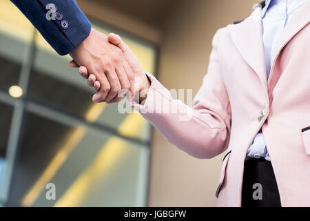 Primo piano Incontro amichevole stretta di mano tra donna e uomo d affari con la luce del sole. Foto Stock