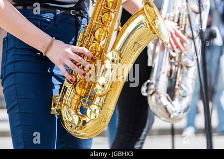 Giovane donna suonare il sassofono durante street fest performance Foto Stock