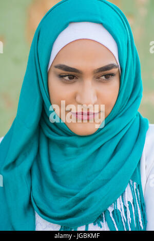 Bella giovane donna musulmana che indossa il hijab guardando lontano Foto Stock