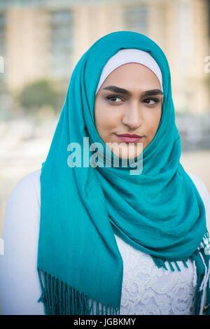 Bella giovane donna musulmana che indossa il hijab guardando lontano Foto Stock