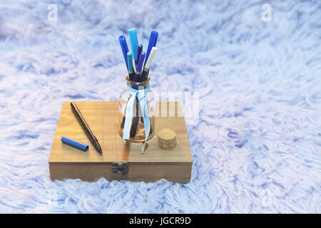 Scatola di legno e un vaso di vetro riempito con penne blu Foto Stock