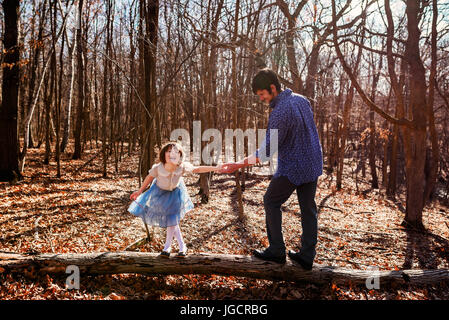 Padre e figlia in piedi su un tronco di albero nella foresta Foto Stock