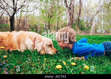 Ragazzo e il suo cane Golden Retriever che giace sull'erba guardandosi l'un l'altro, Stati Uniti Foto Stock