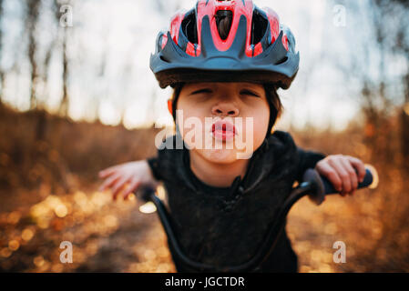 Ragazzo su una bicicletta che indossa un casco il raggrinzimento delle labbra Foto Stock