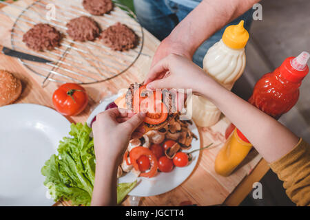 Vista parziale di papà e figlio la cottura della carne Hamburger insieme Foto Stock