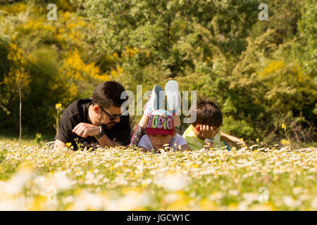 Padre giacente nel parco con due figli Foto Stock