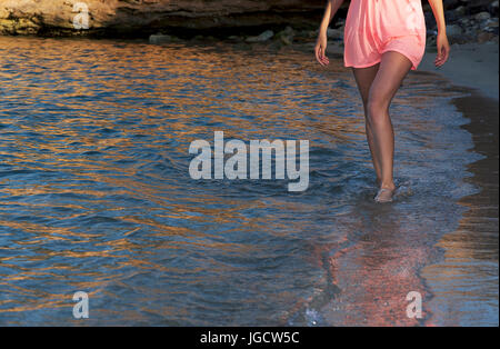 La donna per le gambe camminando sulla spiaggia nel surf, Marsaxlokk, Malta Foto Stock