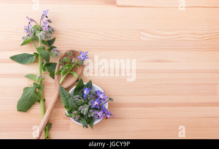 Ciotola e cucchiaio di legno con borragine Foto Stock