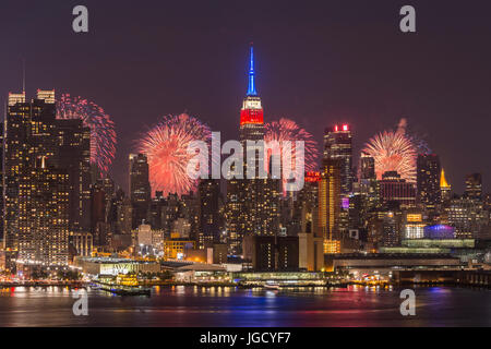 L annuale Macy's quarta di luglio mostra fuochi d'artificio illumina il cielo dietro la skyline di Manhattan a New York City come viste attraverso il fiume Hudson. Foto Stock