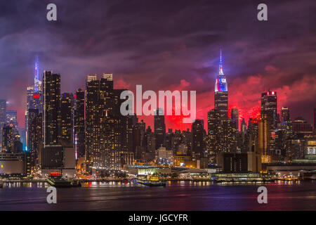 L annuale Macy's quarta di luglio mostra fuochi d'artificio illumina il cielo dietro la skyline di Manhattan a New York City come viste attraverso il fiume Hudson. Foto Stock