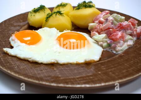 Uovo fritto con patate fresche e pomodoro insalata di cetrioli. Foto Stock