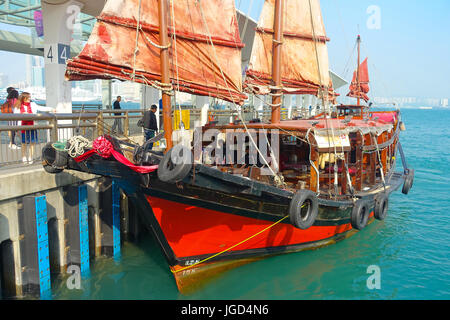 HONG KONG, CINA - 26 gennaio 2017: turistici in barca a vela a Porto, Vista panoramica del cinese tradizionale in legno nave a vela con vele di rosso. Grattacieli. Foto Stock