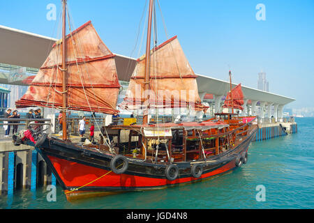 HONG KONG, CINA - 26 gennaio 2017: turistici in barca a vela a Porto, Vista panoramica del cinese tradizionale in legno nave a vela con vele di rosso. Grattacieli. Foto Stock