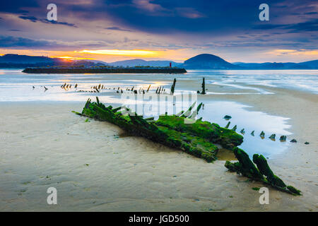 Spiaggia di marea e barche rimane al tramonto. Foto Stock